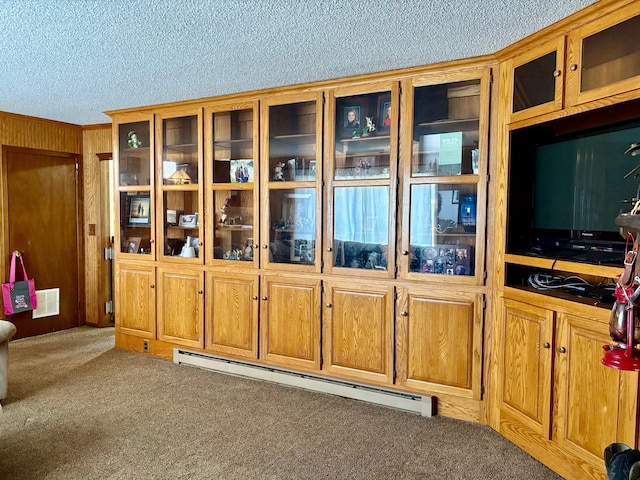 interior details with a textured ceiling, a baseboard heating unit, wood walls, carpet flooring, and visible vents