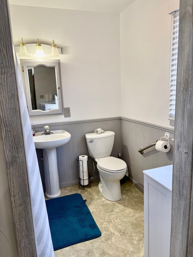 bathroom featuring wainscoting, a sink, and toilet