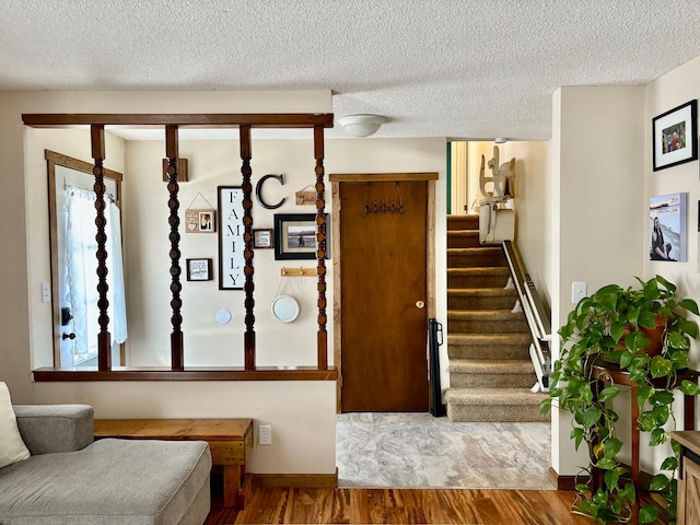 foyer entrance with plenty of natural light, a textured ceiling, stairway, and wood finished floors