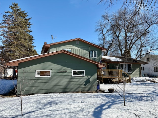 snow covered back of property with a deck