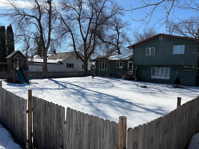 yard covered in snow featuring a fenced backyard and a playground