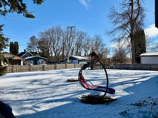 yard layered in snow featuring fence and playground community