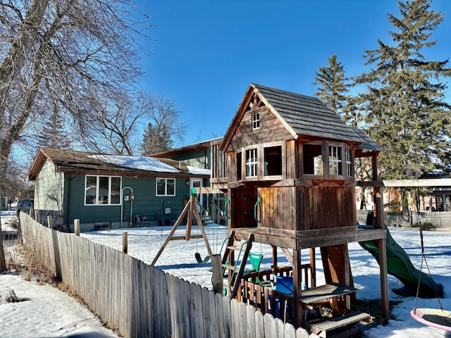 snow covered playground featuring a playground and fence