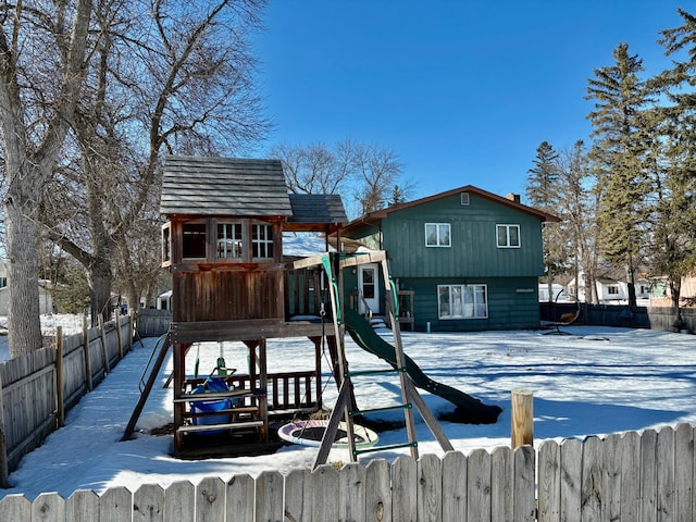 snow covered playground featuring fence and a playground