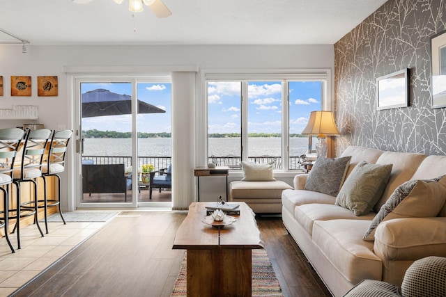 living room with wallpapered walls, plenty of natural light, an accent wall, and wood finished floors