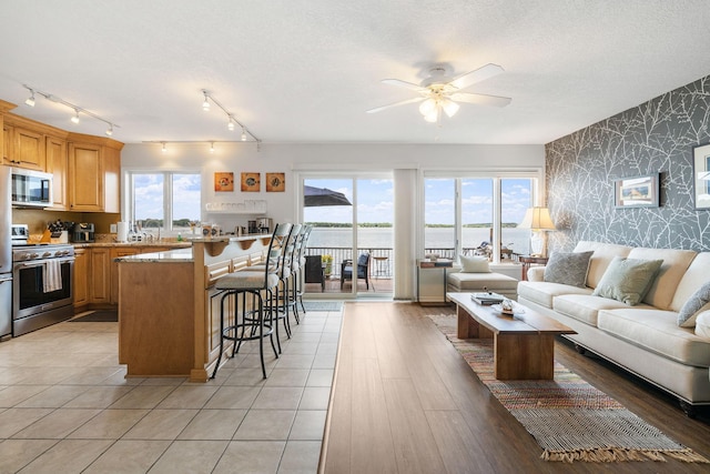 kitchen featuring a breakfast bar, stainless steel appliances, open floor plan, a textured ceiling, and wallpapered walls