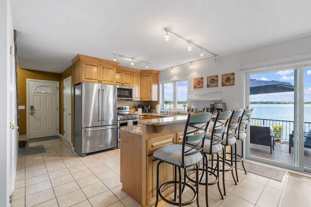 kitchen featuring light tile patterned floors, high quality appliances, light stone counters, and a breakfast bar