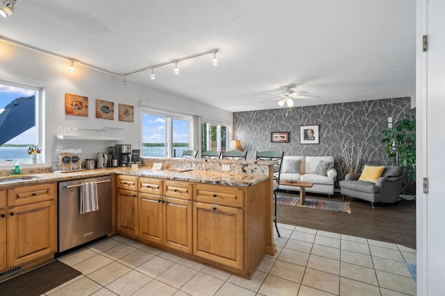 kitchen with light tile patterned floors, a peninsula, open floor plan, dishwasher, and wallpapered walls