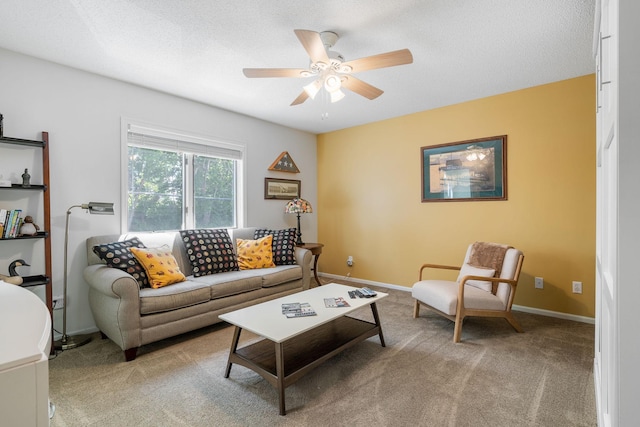 living area with a textured ceiling, ceiling fan, baseboards, and light colored carpet