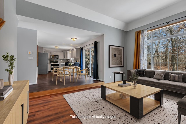 living room featuring dark wood finished floors, a healthy amount of sunlight, and baseboards