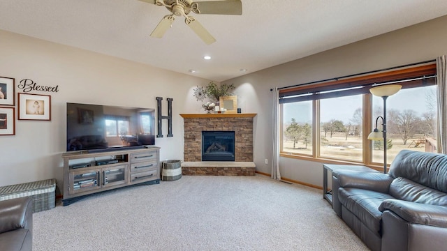 carpeted living room with a stone fireplace, recessed lighting, baseboards, and ceiling fan