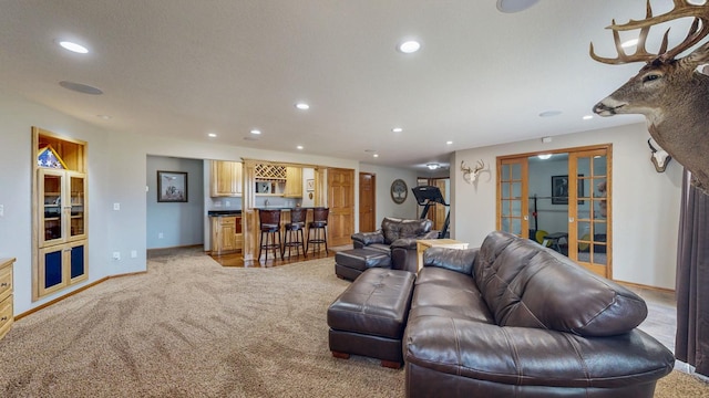 living area with baseboards, light colored carpet, recessed lighting, bar, and french doors