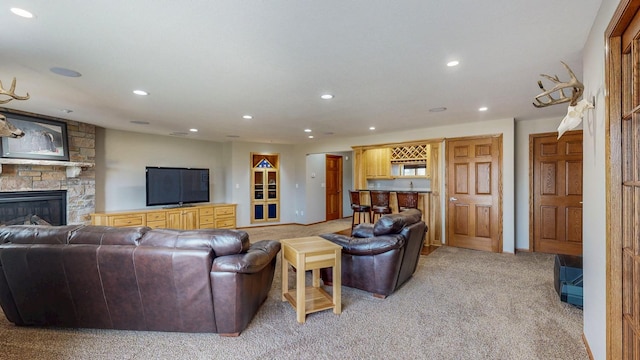 living area featuring recessed lighting, bar, light colored carpet, and a stone fireplace