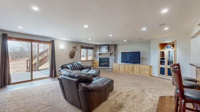 living room featuring a textured ceiling, recessed lighting, a fireplace, and light carpet