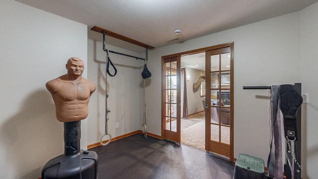 exercise room with french doors, a textured ceiling, and baseboards