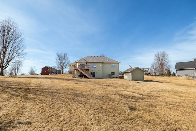 back of house featuring a storage unit, an outbuilding, a lawn, and stairway