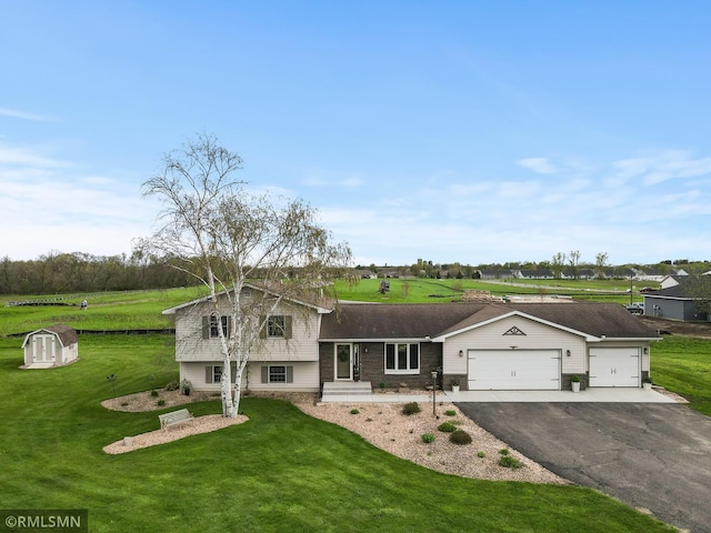 split level home featuring aphalt driveway, an outbuilding, a front yard, a shed, and a garage