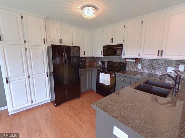 kitchen featuring black appliances, light wood finished floors, a sink, and white cabinets