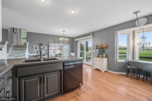 kitchen featuring a chandelier, dishwasher, light wood finished floors, and a sink