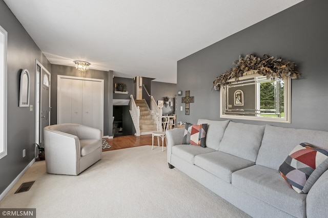 carpeted living room with stairway, visible vents, and baseboards