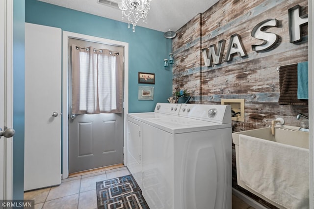 laundry area with washer and clothes dryer, an accent wall, light tile patterned flooring, a sink, and laundry area