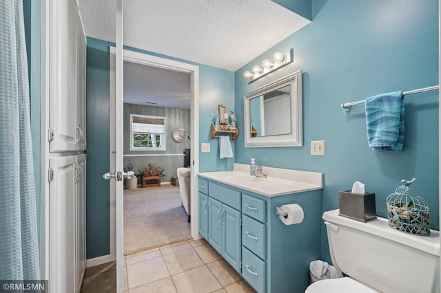 bathroom with baseboards, toilet, tile patterned floors, a textured ceiling, and vanity