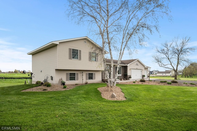 back of property featuring driveway, an attached garage, and a yard