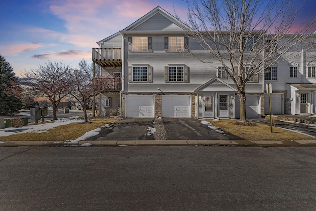 townhome / multi-family property featuring a balcony, a garage, and driveway