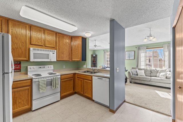 kitchen featuring a sink, white appliances, open floor plan, and light countertops