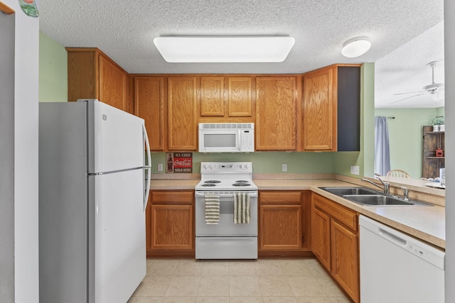 kitchen with a sink, white appliances, brown cabinetry, and light countertops