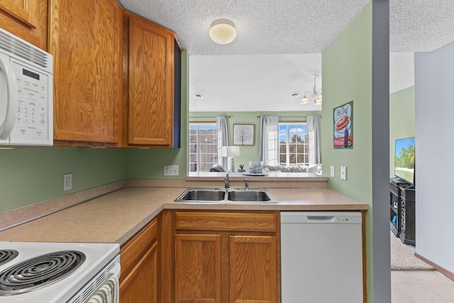 kitchen featuring white appliances, a sink, light countertops, a textured ceiling, and brown cabinets