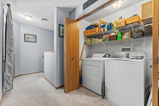 clothes washing area with washer and clothes dryer, laundry area, a textured ceiling, and visible vents