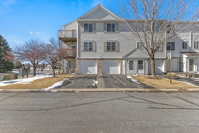 townhome / multi-family property featuring an attached garage, a balcony, and driveway