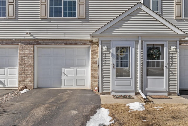 view of exterior entry with driveway and an attached garage