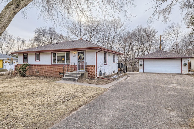 view of front of home featuring an outbuilding, roof with shingles, stucco siding, a detached garage, and brick siding