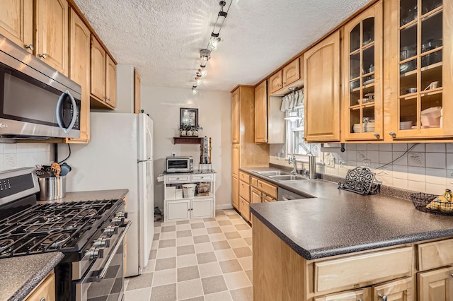 kitchen featuring dark countertops, light floors, appliances with stainless steel finishes, and glass insert cabinets