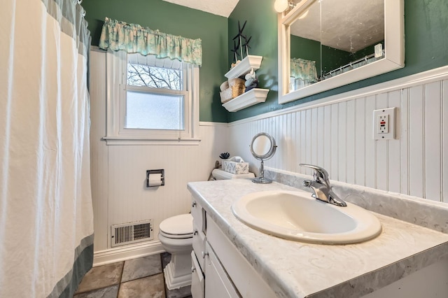 bathroom featuring visible vents, toilet, a shower with shower curtain, wainscoting, and vanity