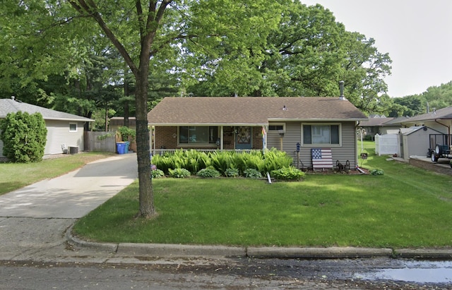 ranch-style house with driveway, brick siding, fence, covered porch, and a front yard