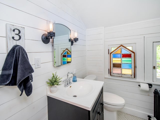 1286 Fairmount Ave, Saint Paul, MN 55105 - bathroom with vanity, toilet, lofted ceiling, wood walls, and tile patterned floors