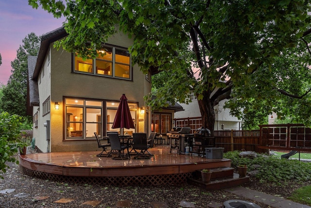 1286 Fairmount Ave, Saint Paul, MN 55105 - back of house at dusk with stucco siding, outdoor dining area, and a wooden deck