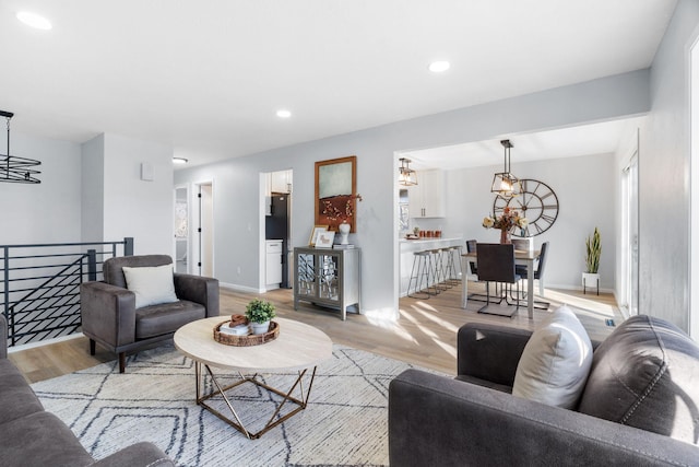 living area with a chandelier, recessed lighting, baseboards, and light wood finished floors