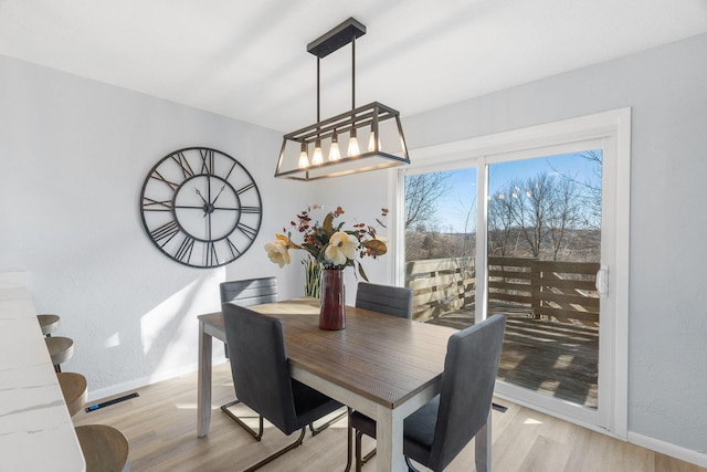 dining space with light wood-type flooring and baseboards