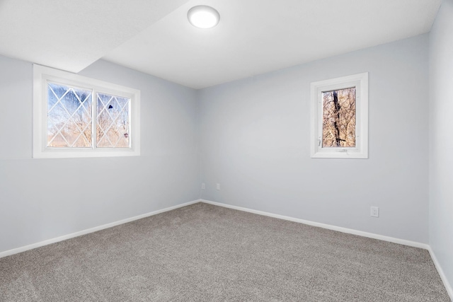 spare room with carpet floors, a wealth of natural light, and baseboards