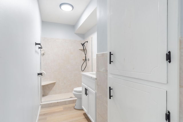 bathroom featuring toilet, a stall shower, wood finished floors, and vanity