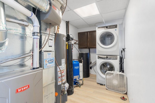 laundry area with gas water heater, cabinet space, stacked washer and clothes dryer, and light wood-style floors