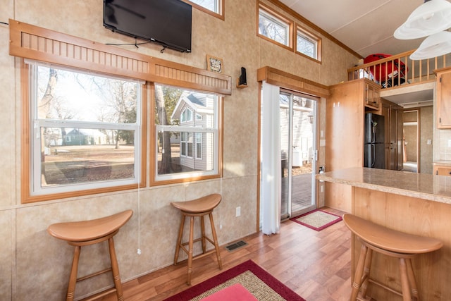 kitchen featuring a kitchen breakfast bar, light wood-style floors, light countertops, and freestanding refrigerator