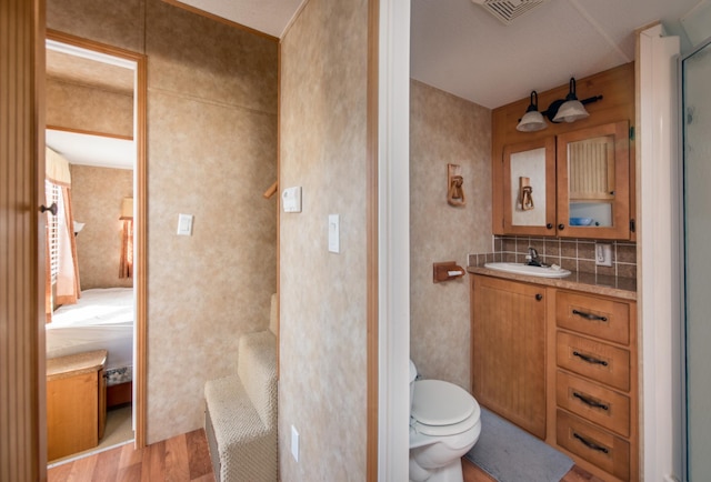 ensuite bathroom with visible vents, toilet, ensuite bathroom, wood finished floors, and vanity