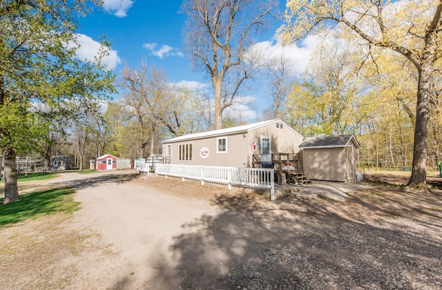 manufactured / mobile home with a shed, driveway, an outdoor structure, and fence