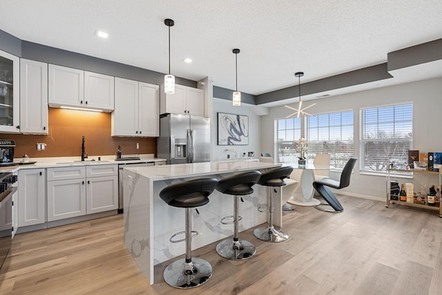 kitchen featuring a breakfast bar, light wood finished floors, appliances with stainless steel finishes, a sink, and a kitchen island