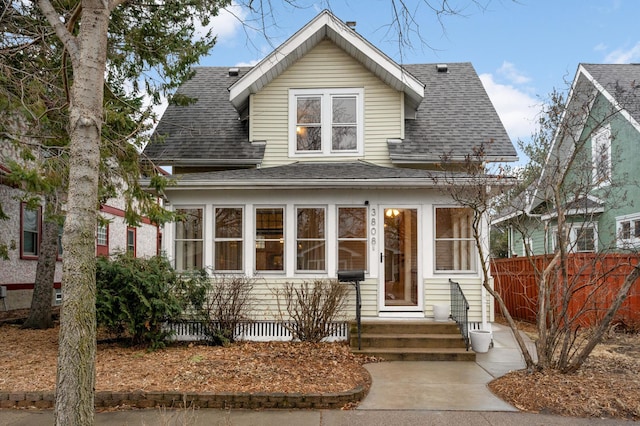 view of front of home with roof with shingles and fence